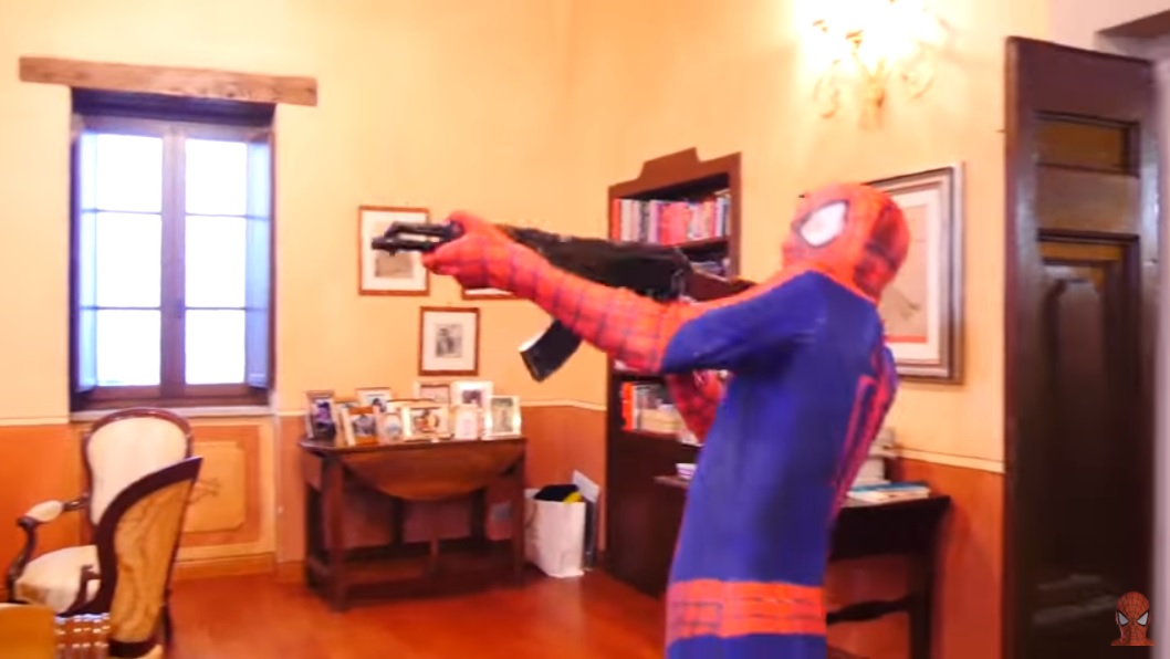 Человек-паук держит в руках пулемет